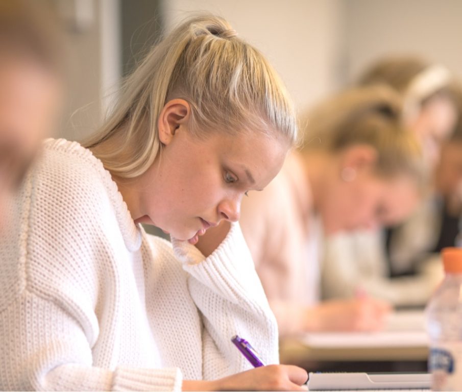 Nuori nainen opiskelee keskittyneesti pöydän ääressä